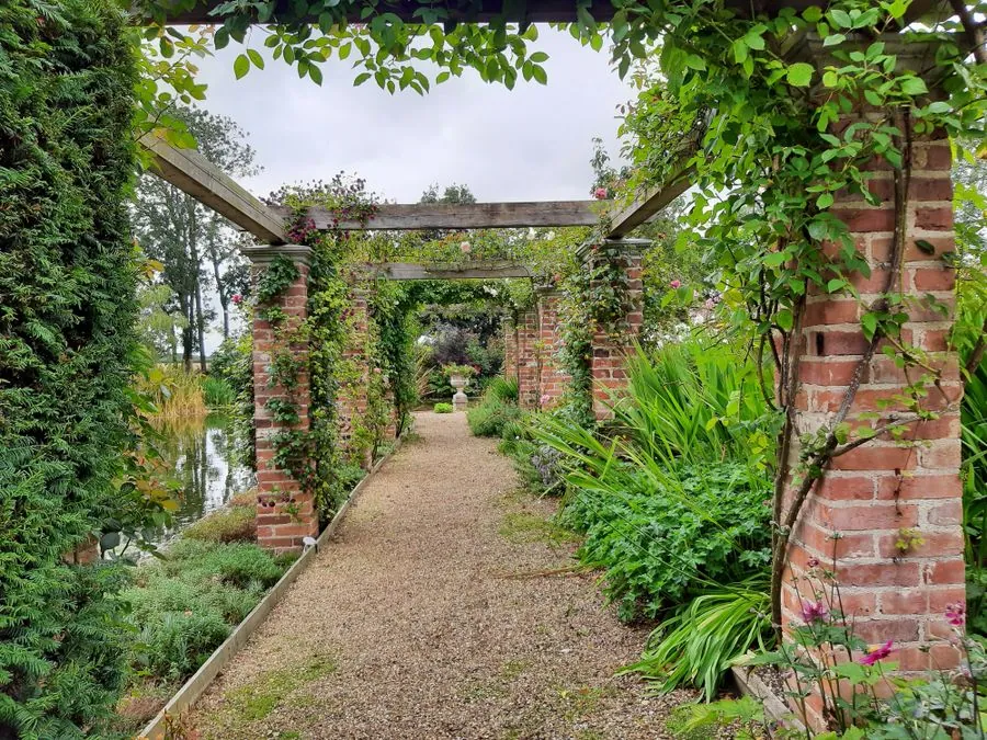 A brick pergola walk covered in climbing plants